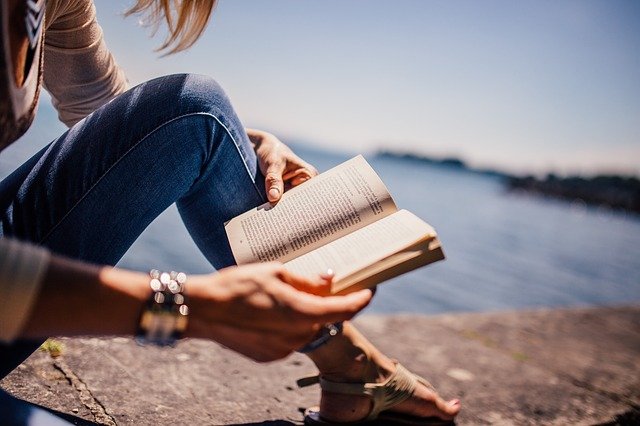 女性が海辺で本を読む様子